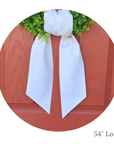 White linen wreath sash with greenery on a wooden surface