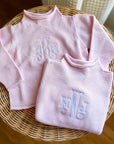 Pink cotton rollneck sweater for kids folded with monogrammed embroidery