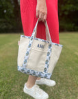 person carrying canvas tote bag with monogrammed initials featuring block print trim