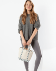 Woman holding a floral-patterned bag against a white background
