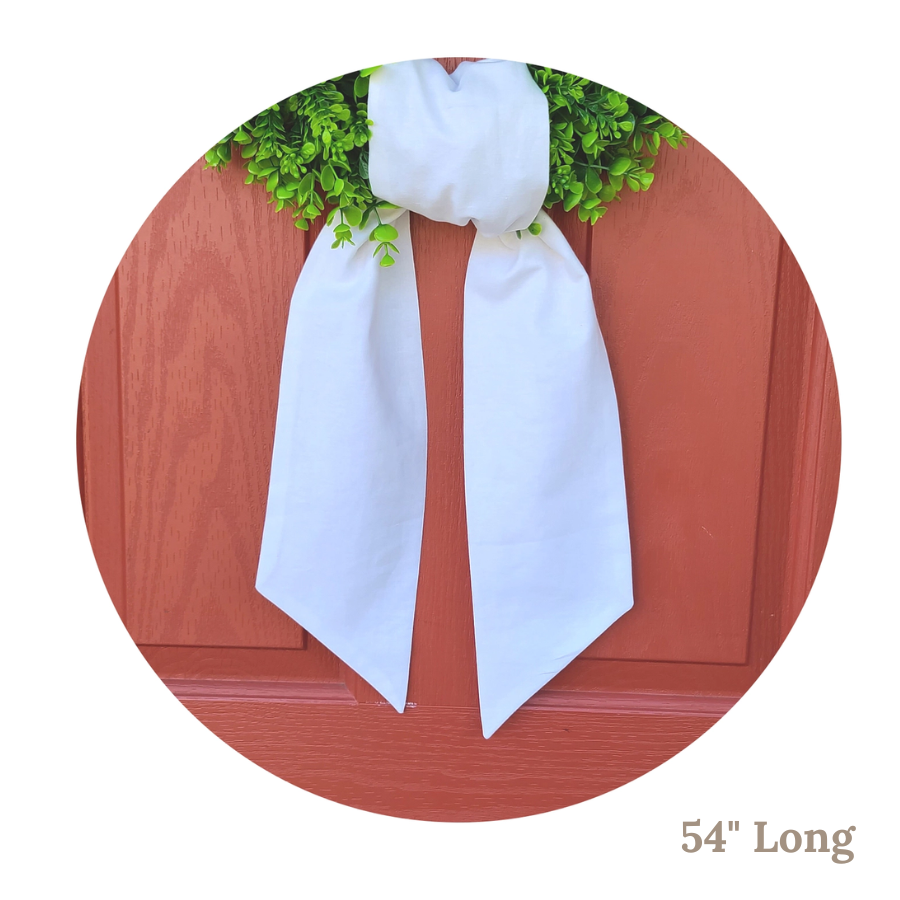 White linen wreath sash with greenery on a wooden surface