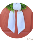 White linen wreath sash with greenery on a wooden surface