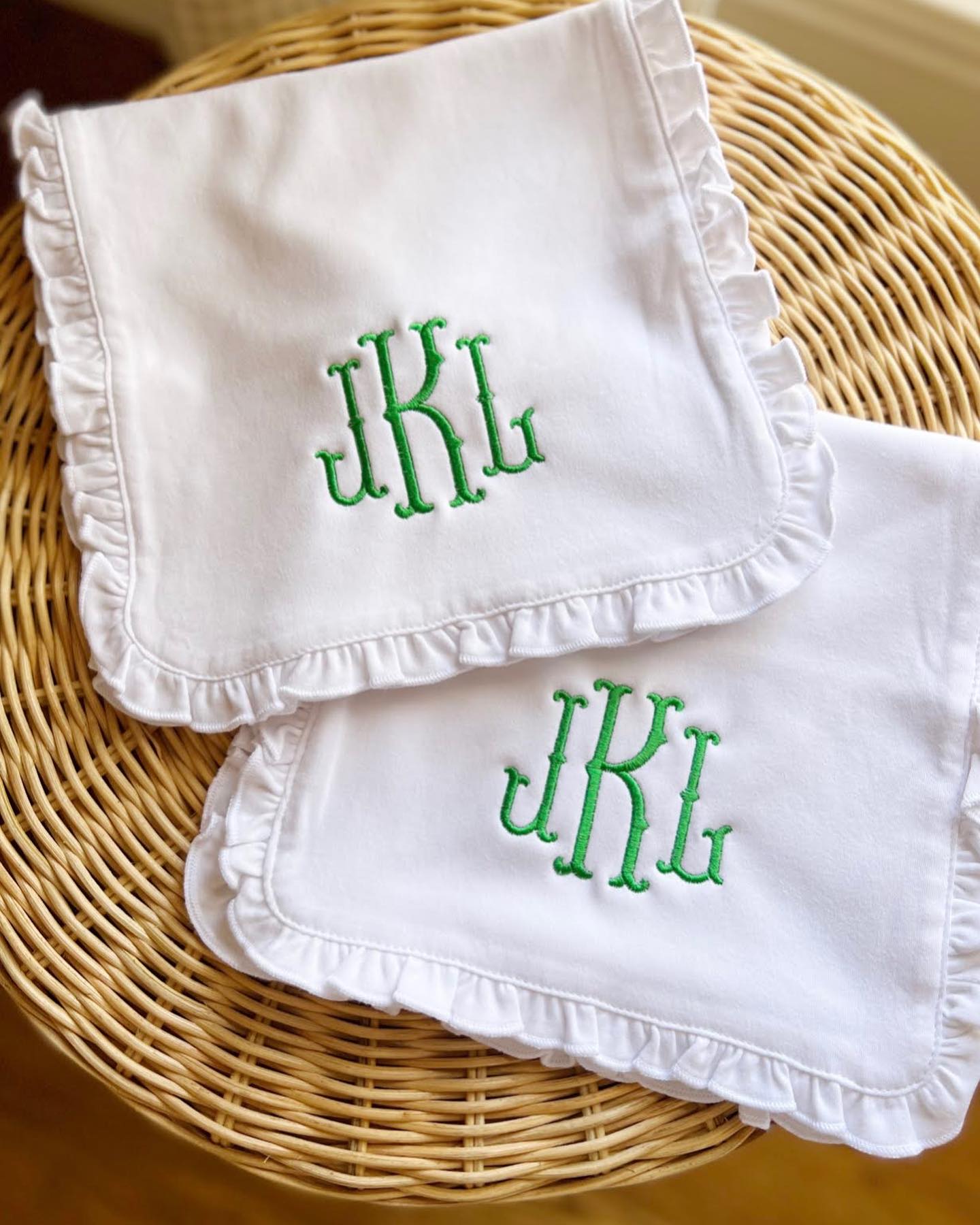 white burp cloths with ruffle edge embroidered with fish tail monogram for baby girl on wicker table