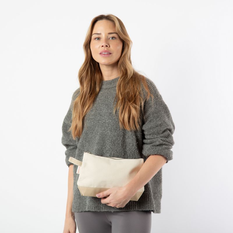 Woman holding a beige clutch bag against a white background
