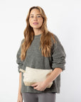 Woman holding a beige clutch bag against a white background