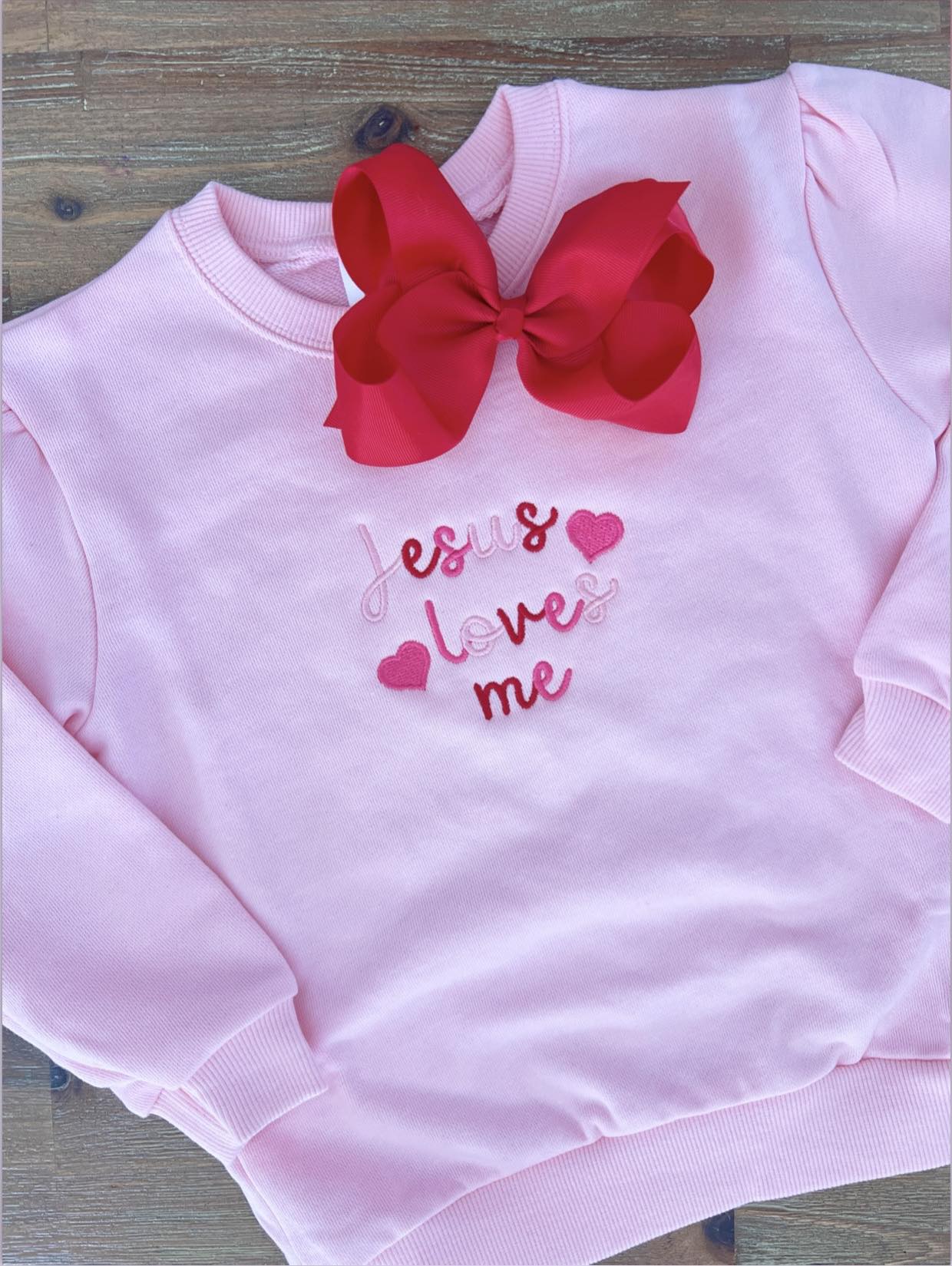 Light pink girls sweatshirt with multicolor ‘Jesus Loves Me’ embroidery in pink and red thread