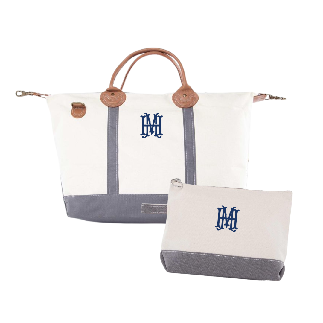White and gray weekender travel bag with brown handles and blue monogram on a white background