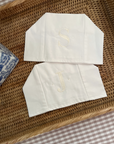two white linen tissue box covers with embroidered initials