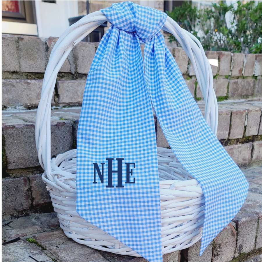 White wicker basket with a blue gingham easter basket sash tied with personalized monogram