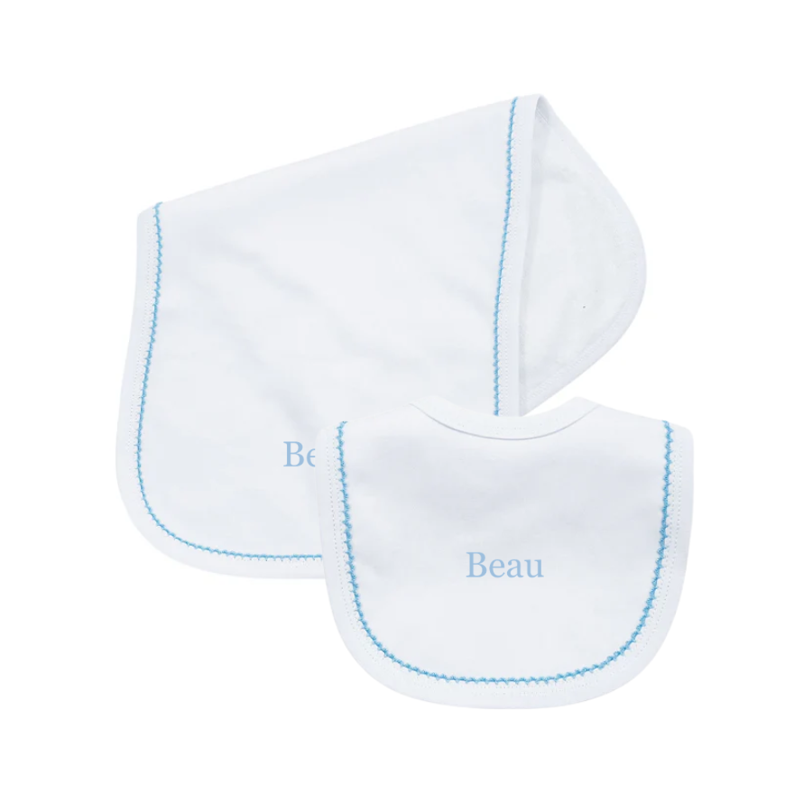 Two white baby bibs with blue embroidery on a white background