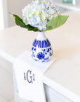 Blue and white ceramic vase with hydrangeas on a surface with a monogram linen guest towel