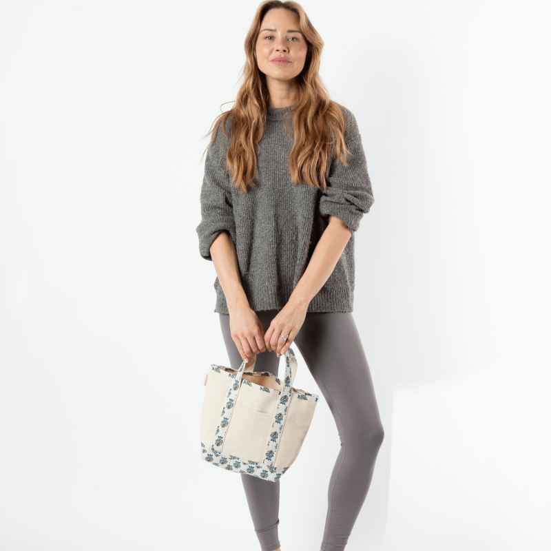 Woman holding a floral-patterned bag against a white background